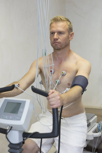 médico con equipo de electrocardiograma haciendo prueba de bicicleta cardiograma al paciente masculino en la clínica hospitalaria
 - Foto, Imagen