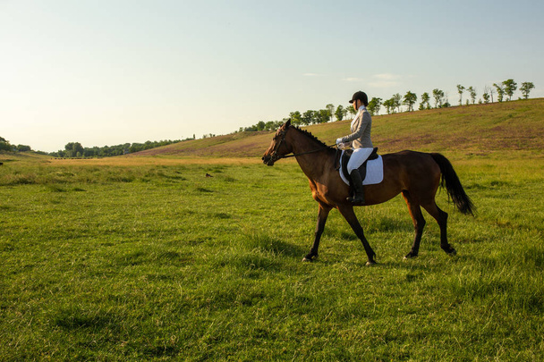 Jeune femme chevauchant un cheval sur le terrain vert - Photo, image