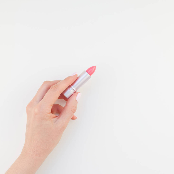 Vrouw hand met pastel manicure Pools bedrijf roze lippenstift geïsoleerd op een witte achtergrond met kopie ruimte. Vierkante sjabloon voor vrouwelijke schoonheid blog social media - Foto, afbeelding