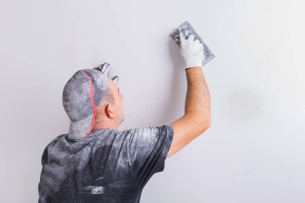 Plasterer polishing a gypsum wall. House renovation concept. - Photo, image