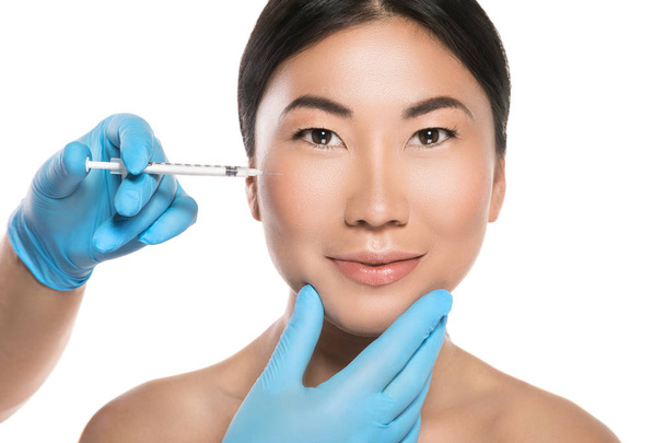 La donna asiatica sta ricevendo iniezioni facciali. Isolato su sfondo bianco
 - Foto, immagini
