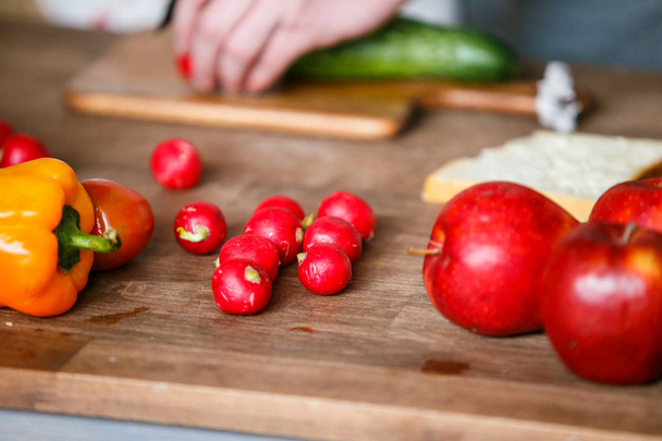 Fresh orange pepper, radish and red apples on the wooden cutting board - Photo, image