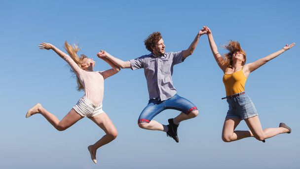 Carefree young friends people jumping outdoor on sky background. Happy women and man having fun. Summer happiness and freedom. - Photo, image