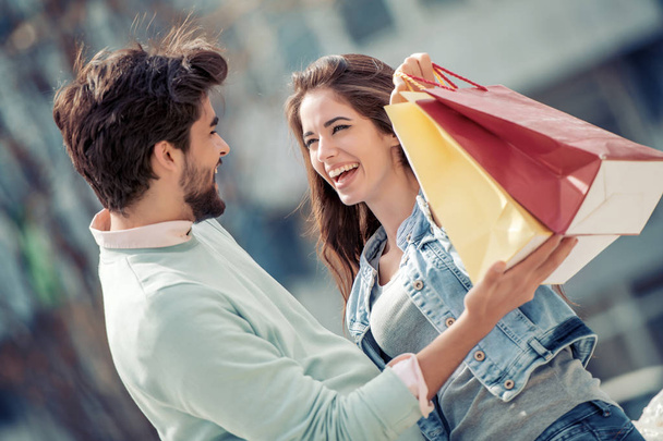 Retrato de pareja joven con bolsas de compras en la ciudad. Gente, venta, amor y concepto de felicidad
. - Foto, imagen