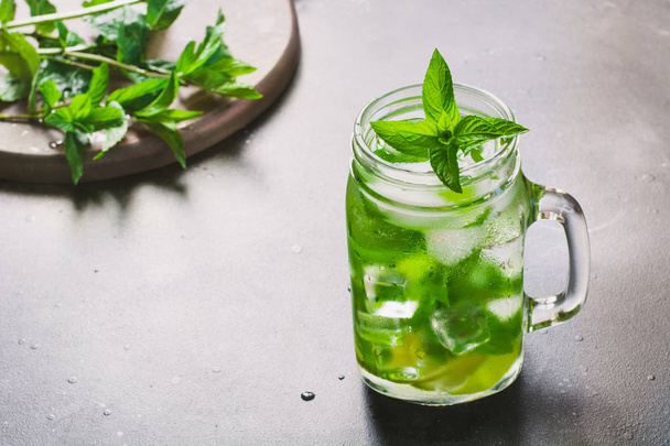 Mojito cocktail in mason jar with garnish on black table. Close up. Copy space for text. - 写真・画像