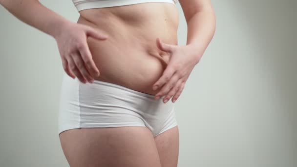 Mujer en ropa interior blanca sostiene su grasa del vientre
. - Metraje, vídeo