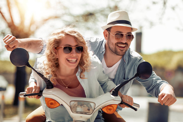 Счастливая молодая пара ездит на скутере, веселится вместе
. - Фото, изображение