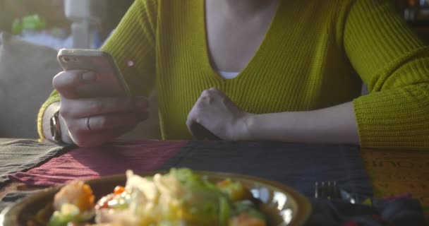 Vrouw in het café met behulp van de smartphone tijdens het wachten. - Video