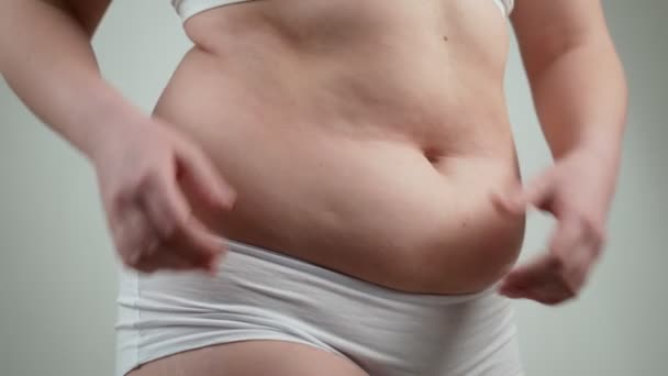 Vrouw in wit ondergoed houdt haar dikke buik. - Video