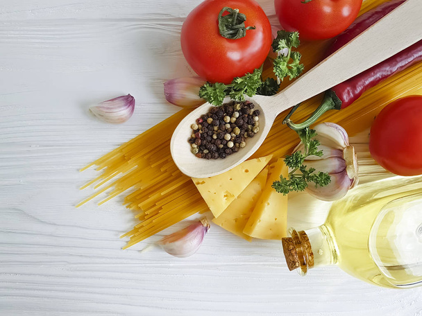 spagetti, paradicsom, fokhagyma, bors, vaj, sajt, egy fából készült háttér - Fotó, kép