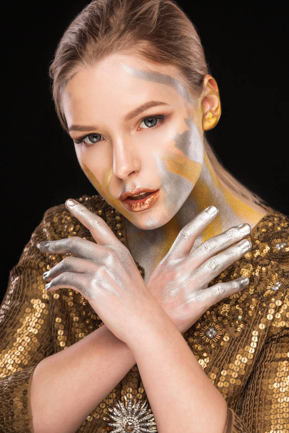 Beauty shoot de jolie femme blonde avec de la peinture dorée et argentée sur son visage et ses mains
 - Photo, image