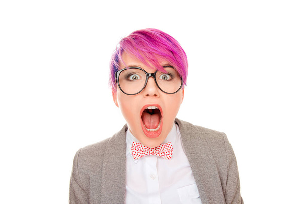 Stylish millennial woman with pink short hair wearing bow tie with glasses and shouting with great amazement at camera on white background - Photo, Image