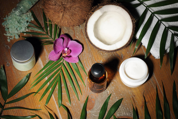 rangschikking van huidverzorgingsproducten, kokosnoot, orchideebloem en palm bladeren - Foto, afbeelding