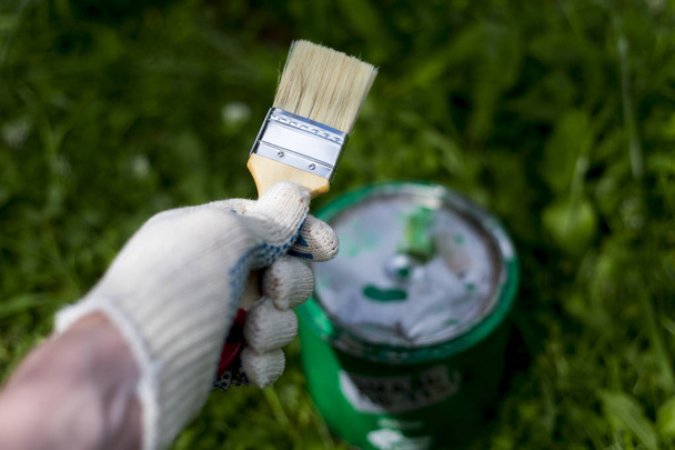 Hand holding a brush on a can with green paint - Photo, Image