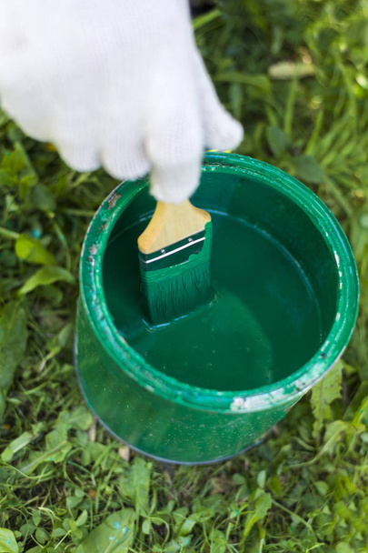 Hand holding a brush on a can with green paint - Φωτογραφία, εικόνα