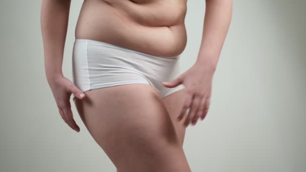 Kobieta w białej bieliźnie trzyma jej biodra tłuszczu. - Materiał filmowy, wideo