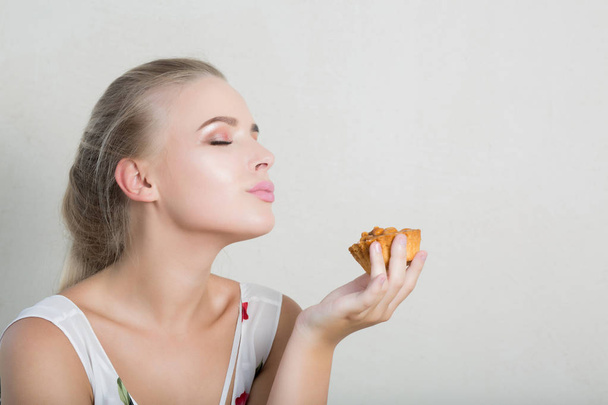 Playful blonde girl having fun with a sweet dessert with nuts. Empty space - 写真・画像
