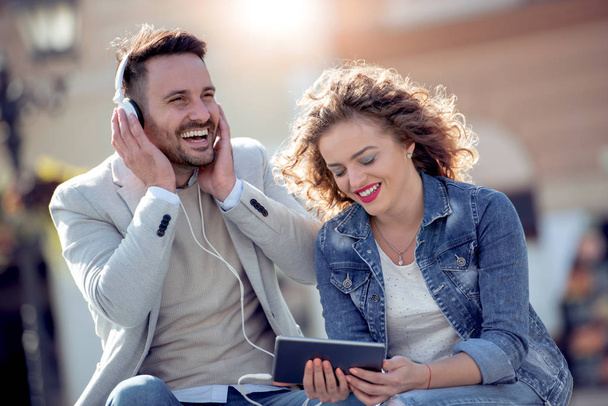 Para w miłości słuchania muzyki na słuchawkach w mieście. - Zdjęcie, obraz