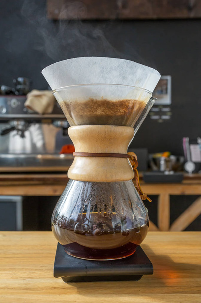 Close-up of brewing coffee in chemex on wooden table - Фото, изображение