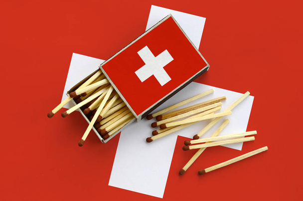 Switzerland flag  is shown on an open matchbox, from which several matches fall and lies on a large flag. - Valokuva, kuva