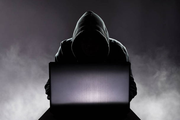 Hacker in front of his computer. Dark face - Foto, afbeelding