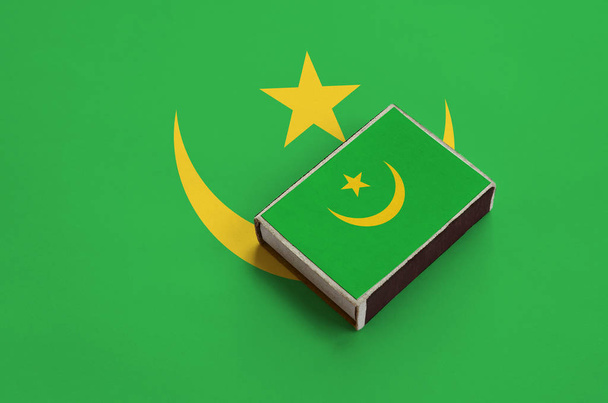 Flaga Mauretanii jest na zdjęciu na matchbox, który leży na dużą flagę. - Zdjęcie, obraz