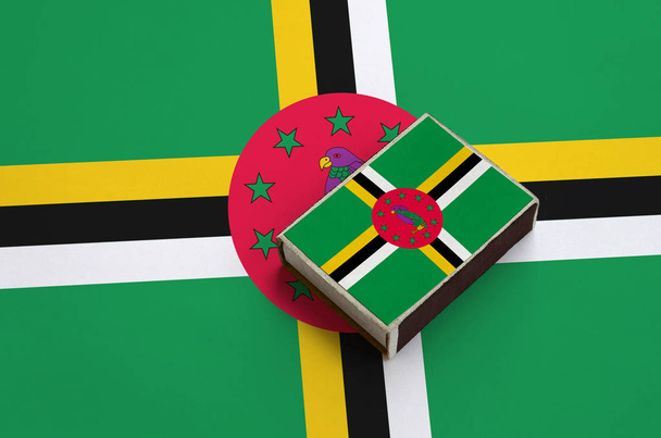 Vlajky Dominika je vyobrazena na krabičce od sirek, které leží na velká vlajka. - Fotografie, Obrázek