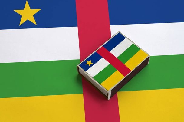 Σημαία της Κεντροαφρικανικής Δημοκρατίας απεικονίζεται σε ένα Σπιρτόκουτο που βρίσκεται σε μια μεγάλη σημαία. - Φωτογραφία, εικόνα