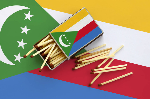 drapeau Comores est affiché sur une boîte d'allumettes ouverte, à partir de laquelle plusieurs matchs tombent et se trouve sur un grand drapeau
. - Photo, image