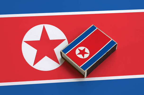 Észak-Korea zászló a képen egy gyufásdoboz rejlik a nagy zászló. - Fotó, kép