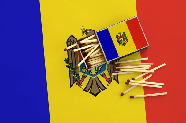 Moldova flag  is shown on an open matchbox, from which several matches fall and lies on a large flag. - Photo, Image