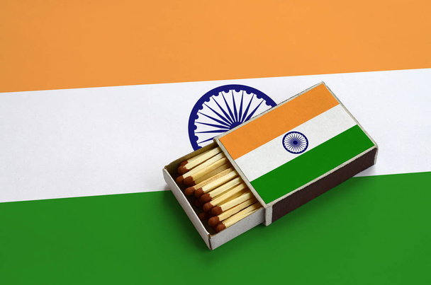 India flag  is shown in an open matchbox, which is filled with matches and lies on a large flag. - Foto, afbeelding