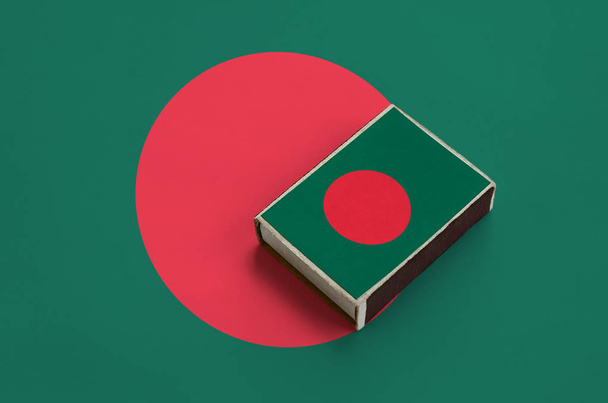 Vlag van Bangladesh is afgebeeld op een luciferdoosje, dat op een grote vlag ligt. - Foto, afbeelding