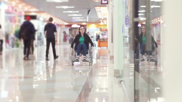 Frau mit Behinderung im Rollstuhl fährt ins Einkaufszentrum und schaut aus den Fenstern - Filmmaterial, Video