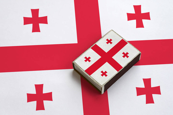 Le drapeau de Géorgie est représenté sur une boîte d'allumettes qui se trouve sur un grand drapeau
. - Photo, image