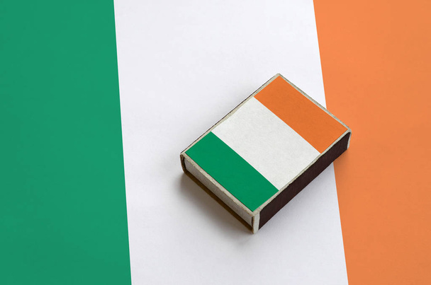 Írország lobogója a képen egy gyufásdoboz rejlik a nagy zászló. - Fotó, kép