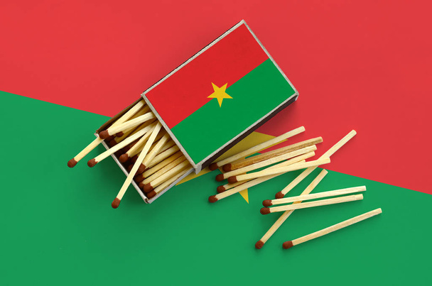Burkina Faso flaga jest się na otwarte matchbox, z których kilka pasuje do upadku i leży na dużą flagę. - Zdjęcie, obraz