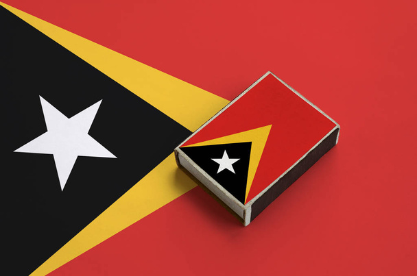 Timoru vlajka je vyobrazena na krabičce od sirek, které leží na velká vlajka. - Fotografie, Obrázek