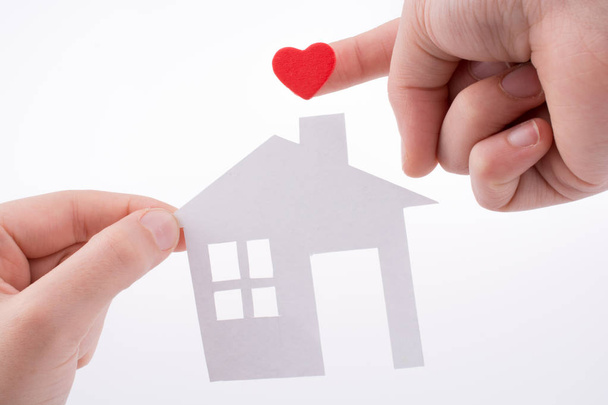 Papír ház és szív alakú kéz a kézben fehér háttér - Fotó, kép