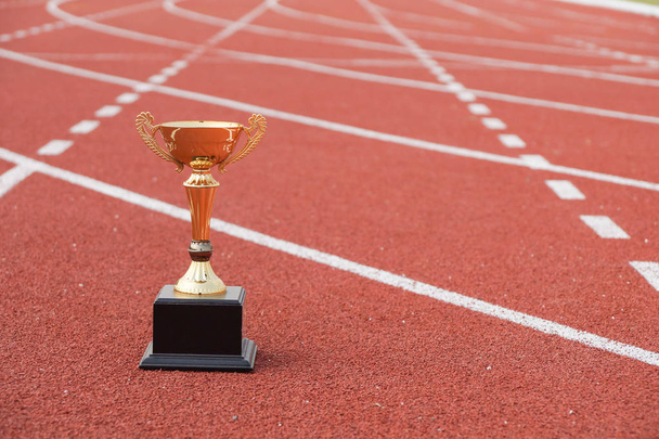 A golden trophy on running track / Competition for success concept - Photo, Image