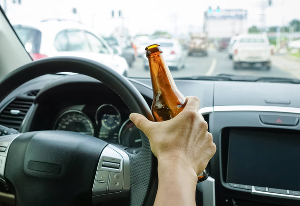 Kierowca, trzymając butelkę alkoholu podczas jazdy / pijany jazdy koncepcja - Zdjęcie, obraz