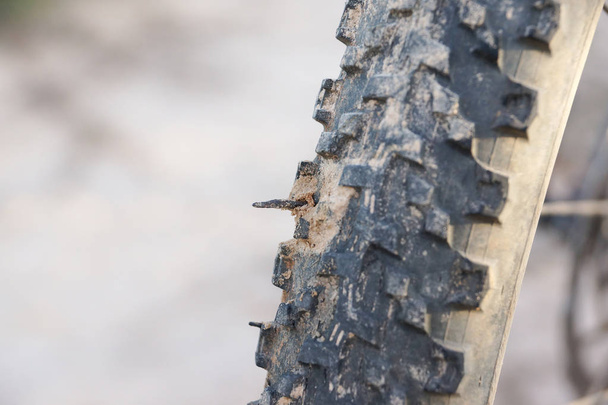 Un pneumatico da mountain bike con un chiodo arrugginito / bicicletta con un concetto di foratura
 - Foto, immagini
