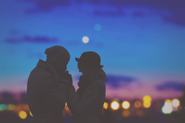 romantic man kissing girlfriend hands on night city background  - Фото, зображення