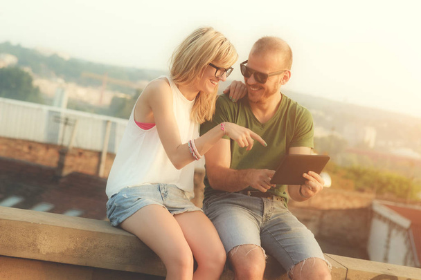 pareja en el amor sentados juntos en la azotea y el uso de tableta pc con paisaje urbano en el fondo
 - Foto, Imagen