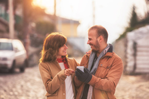 couple doux en utilisant smartphone tout en se tenant debout sur fond de rue floue
  - Photo, image