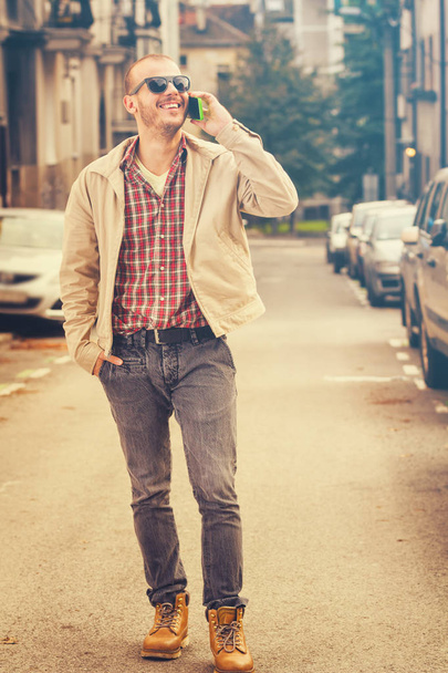 mosolygó ember elegáns ruhában, beszélő smartphone rövid idő Gyaloglás utca  - Fotó, kép