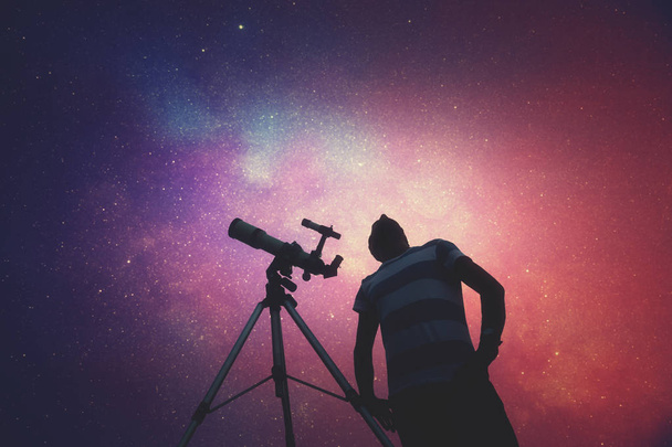 Young man using a telescope at night - Photo, Image