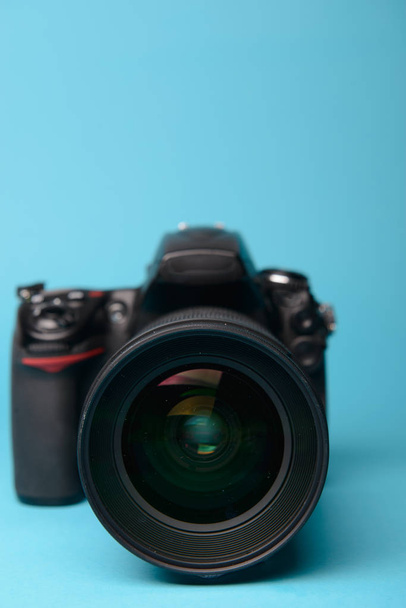 Professionele moderne DSLR camera tegen blauwe achtergrond - Foto, afbeelding