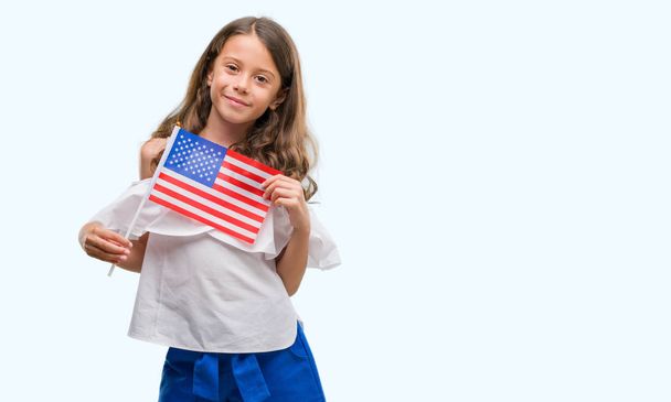 Brunette hispanic girl holding flag of United States of America with a happy face standing and smiling with a confident smile showing teeth - Photo, Image