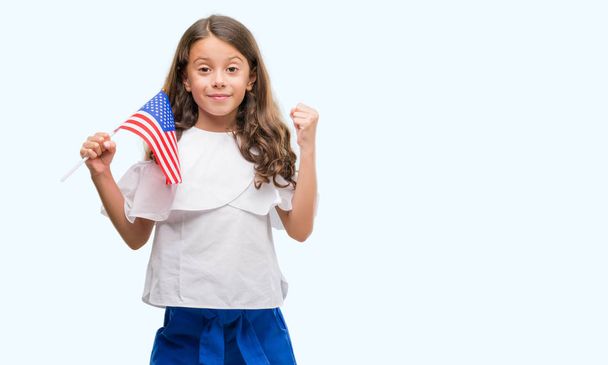 Bruna ragazza ispanica che tiene la bandiera degli Stati Uniti d'America urlando orgoglioso e celebrando la vittoria e il successo molto eccitato, esultante emozione
 - Foto, immagini